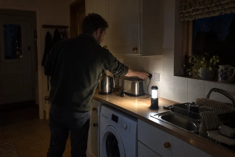 Man unplugging kitchen appliances by torchlight in an Edzell cottage
